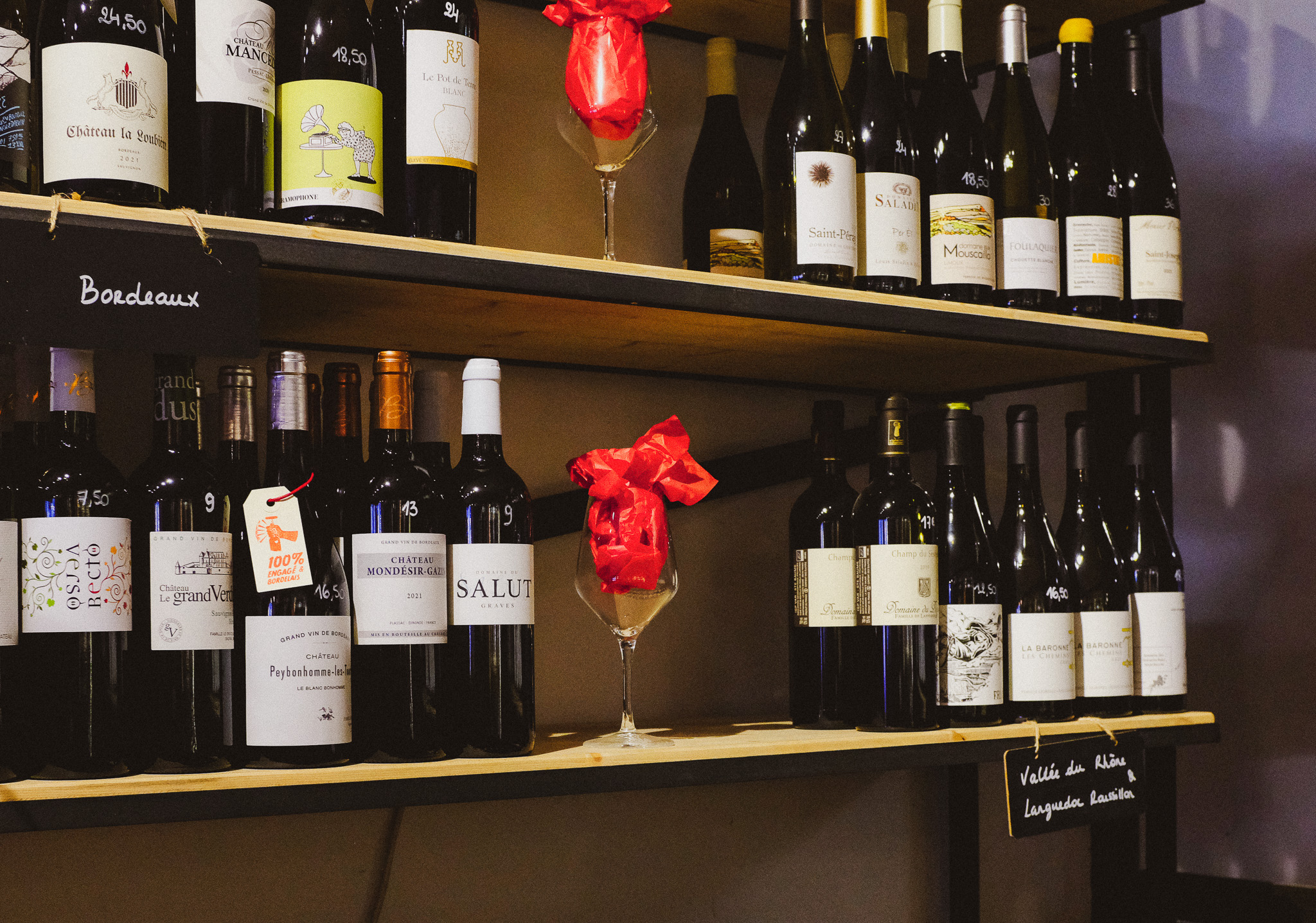 Deux étagères remplies de bouteilles de vins de Bordeaux et de la Vallée du Rhône.