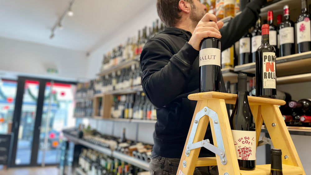caviste sur échelle qui range ses bouteilles