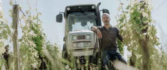 Vigneron accoudé contre son tracteur.