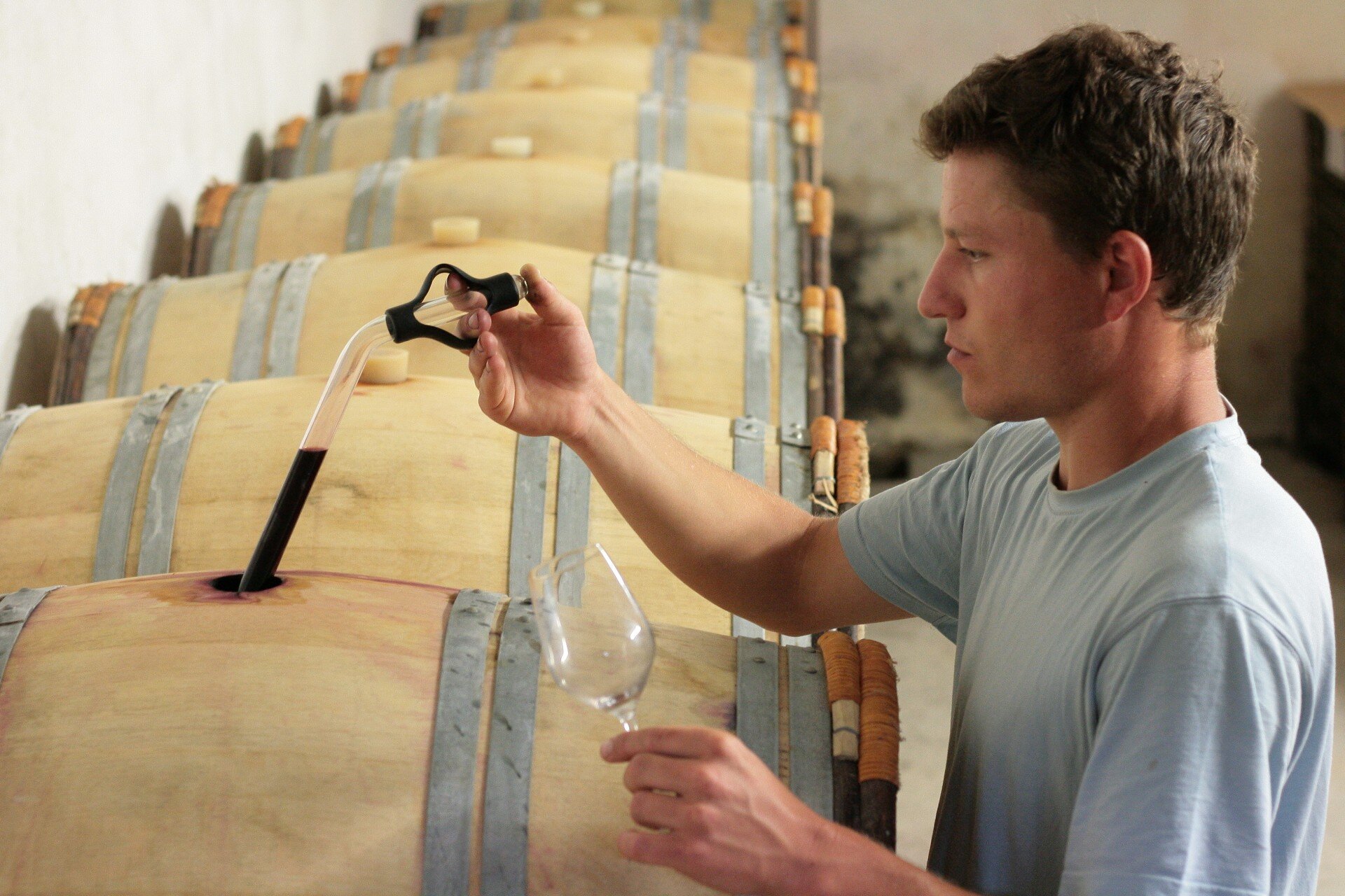 Un vigneron testant le vin d'un tonneau.